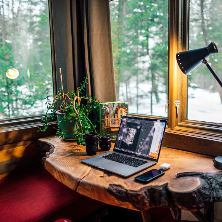 A cosy home office with laptop open to a website on a wooden desk.